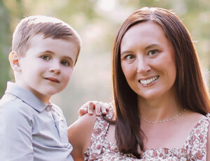 Closeup of Jessica Hubbard holding her young son in a sunny outdoor setting.