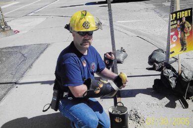 A fire fighter in a hard hat collects donations in a boot