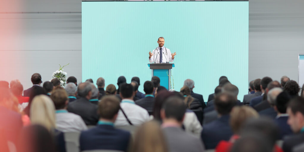 Male doctor giving a speech on a podium at a conference in front of an audience