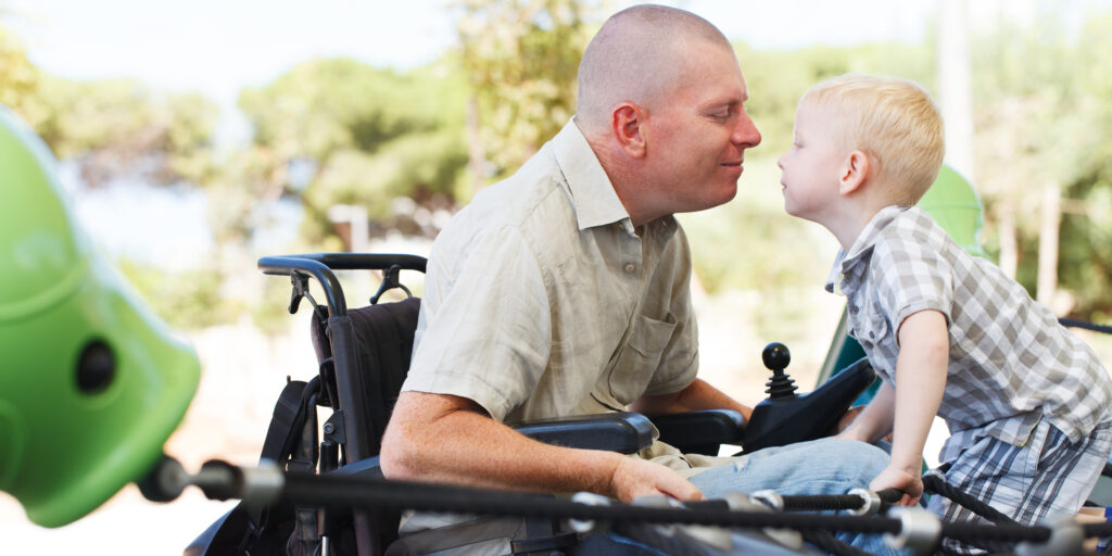 Disabled Father play with his little son on the playground