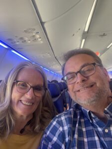 Selfie of Doug Clough and his wife seated on an airplane.