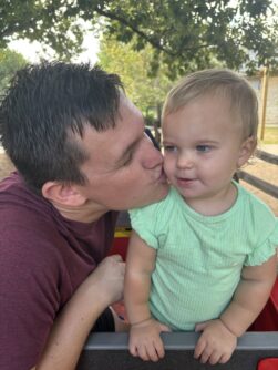 A young man kisses a toddler's cheek