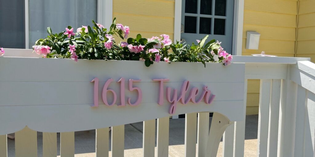 Exterior shot of a yellow beach house with flower boxes