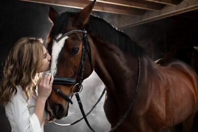 A woman kisses a horse on the nose