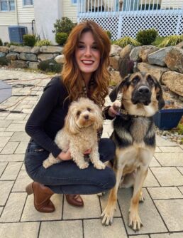 A woman with brown hair poses with two dogs