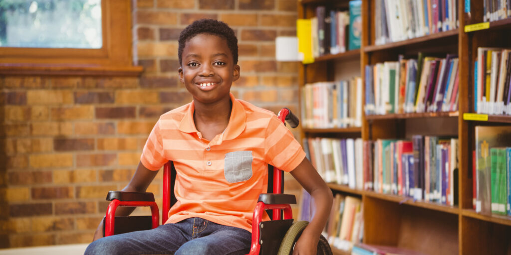 Portrait of little boy sitting in wheelchair at the library
