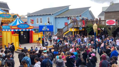 A magician stage with a large crowd gathered around it.