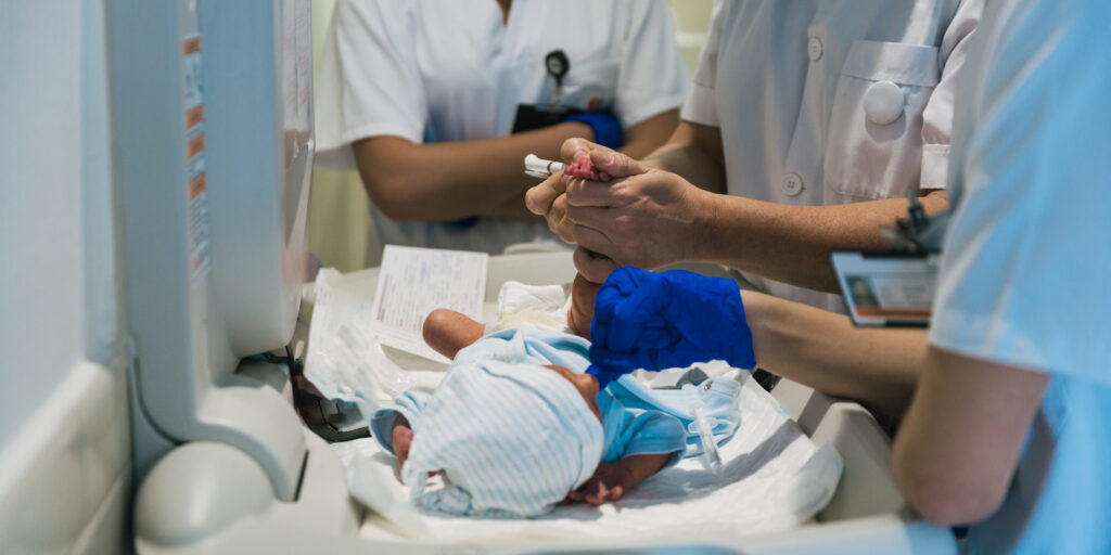 Team of professional doctors and nurses examining newborn baby at the hospital. Healthcare and medicine concept.