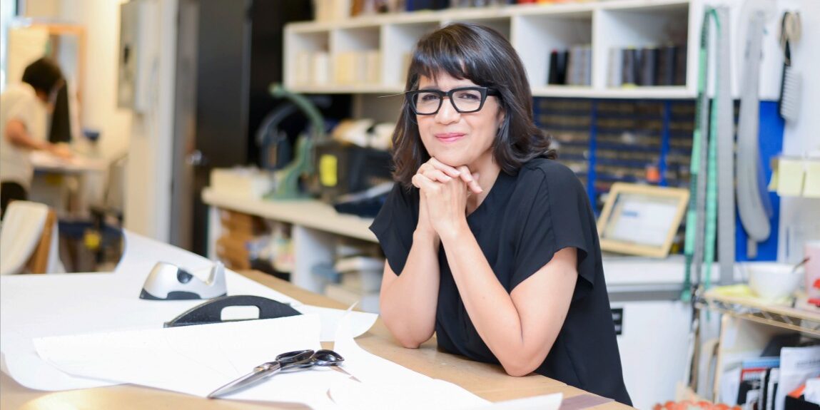 Fashion designer Izzy Camilleri sitting at a table in her design studio