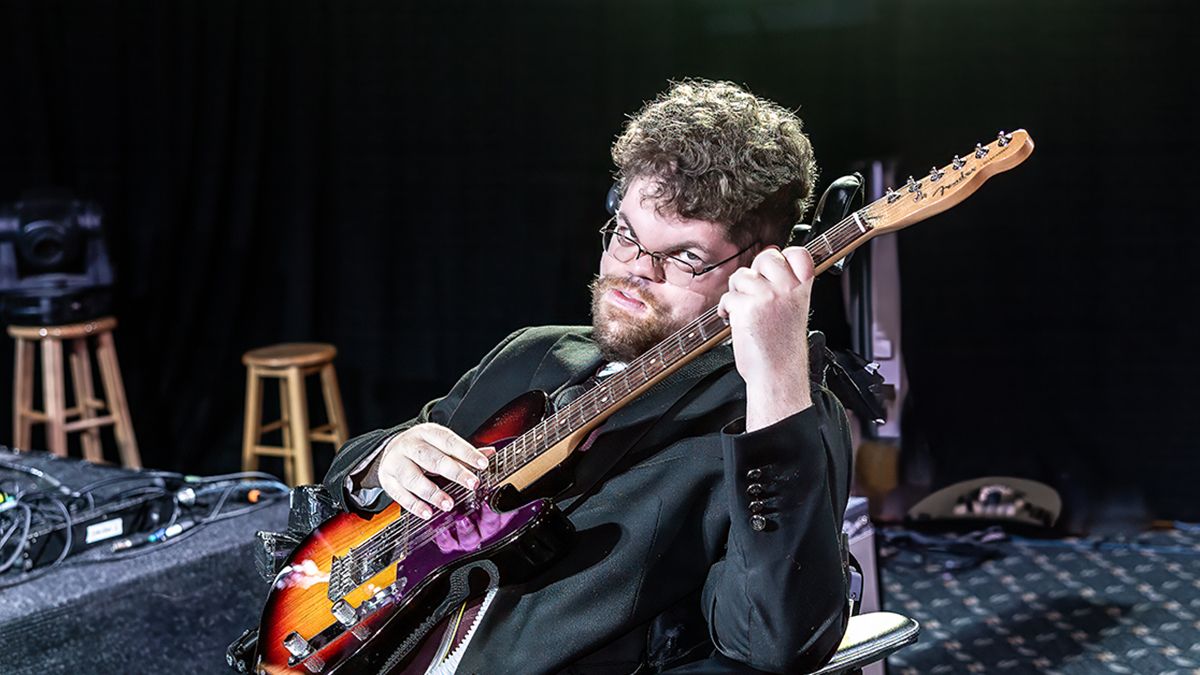 Singer-songwriter Lucas Garrett holds an electric guitar and looks up at the camera with a serious expression.