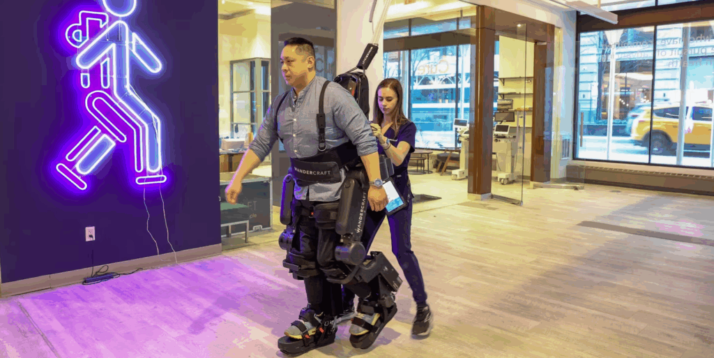 A patient walks using Wandercraft’s Atalante X hands-free exoskeleton under the supervision of a physical therapist at Walk in New York.