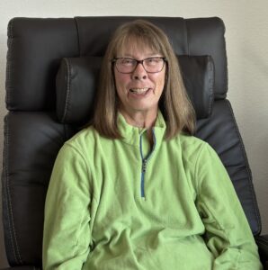 Closeup of Mary Jane Niles smiling while sitting in a black leather recliner.