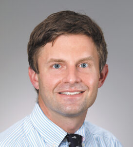 Headshot of doctor Christopher Grunseich, a light-skinned man with short brown hair and blue eyes.
