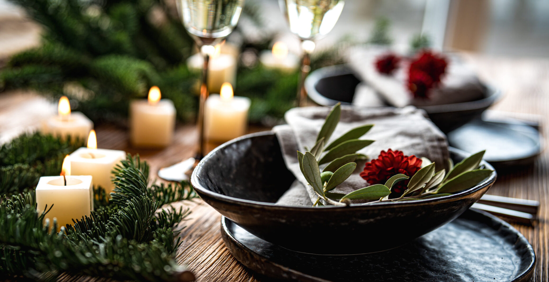 Festive table decoration with candle lights on wooden table with fir branches.