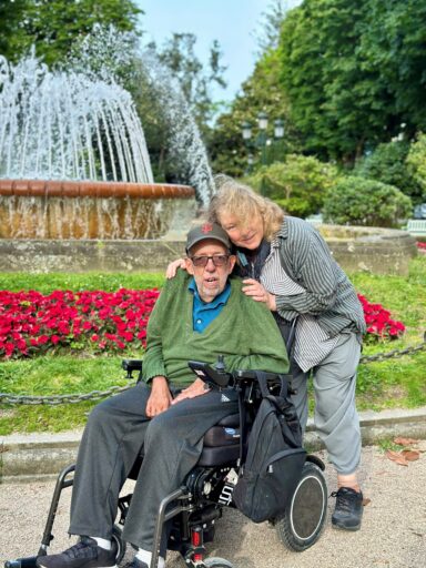 A man in a wheelchair and a woman pose in front of a fountain in Vigo, Spain