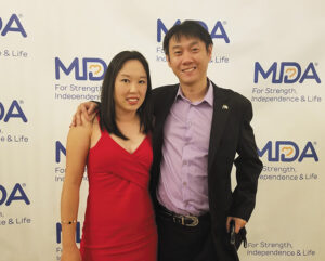 Spouses Angela Lek, PhD, MDA’s Chief Research Officer, and Monkol Lek, PhD, a Yale geneticist, pose at an event in front of a backdrop with the MDA logo.