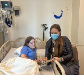 A girl in a hospital bed studies with a teacher 