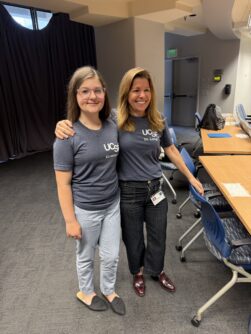 A young girl poses with a woman at a conference. 