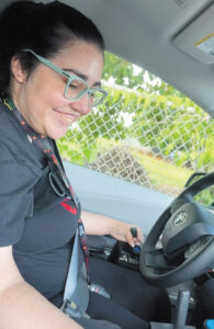 Diana Colón Vega sits in the driver’s seat of an adapted van, with her left hand on a joystick control.