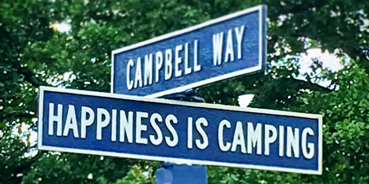 A street sign that reads Happiness is Camping