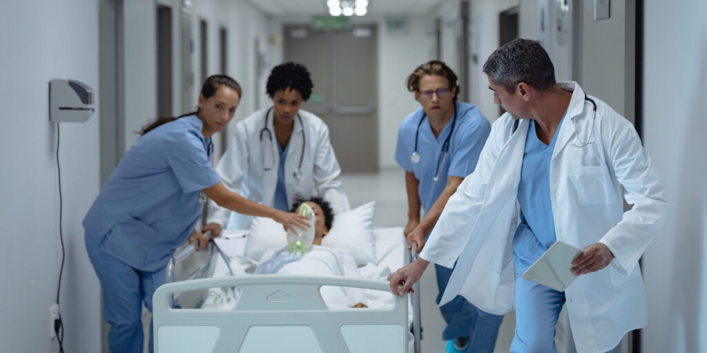 Front view of medical diverse team pushing emergency stretcher bed in the corridor at hospital