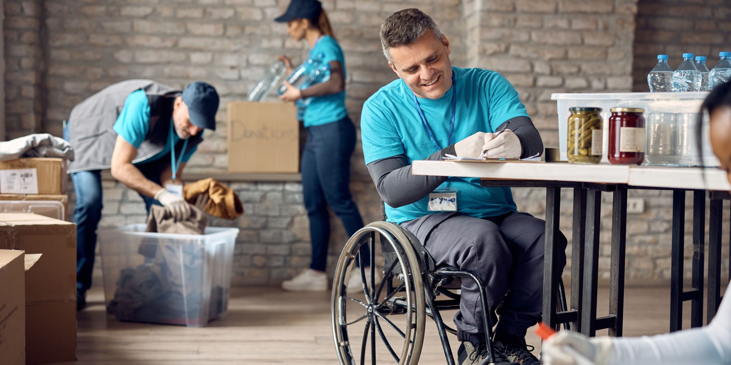 Happy volunteer in wheelchair taking notes while working at donation center.
