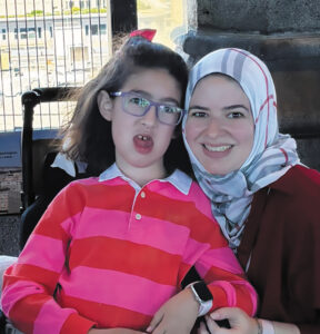 Tala Rifai leaning in toward her daughter, Celine, who is sitting in a black wheelchair.