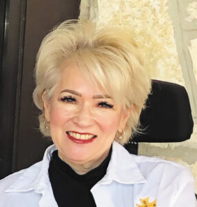 Closeup of Jo Ann S. Rincon outdoors in front of a stone building.
