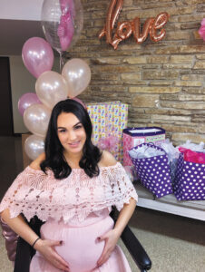 Cassidy Nilles, while pregnant, sits in her wheelchair during her baby shower, with ballons and gifts arrayed behind her.