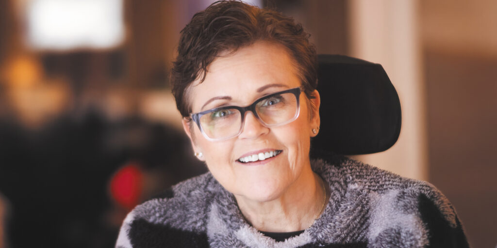 Closeup of Sharon Townsend smiling at the camera wearing glasses and a fuzzy black and gray sweater.