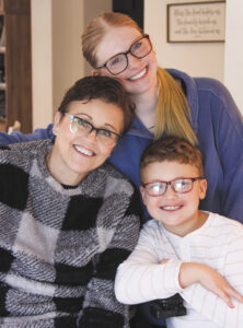 Sharon Townsend sits in her power wheelchair, a teenage girl has an arm around her shoulders, and a middle school-age boy leans on her wheelchair arm rest.