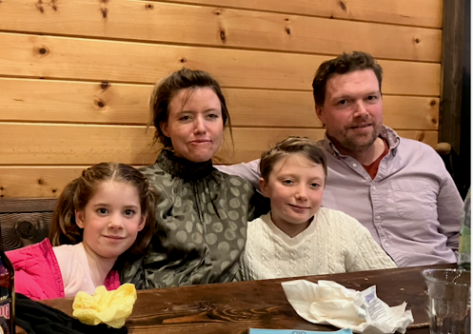 A mother and father sit with two children at a dinner table