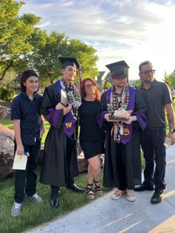 A family of five poses for a photo, two teenage sons wear graduation cap and gowns