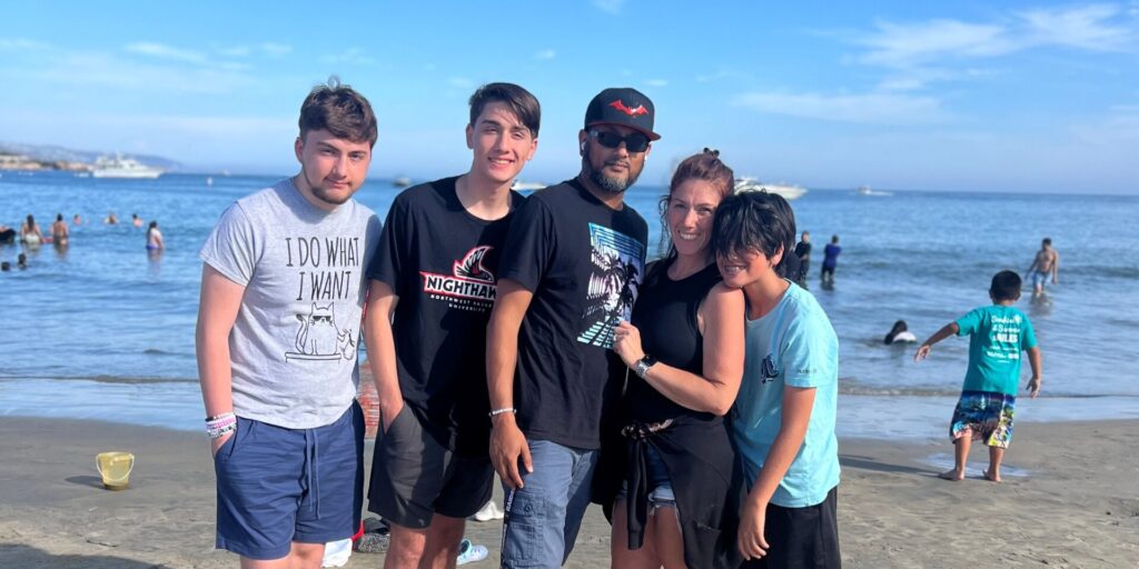 A family of five stands on a beach for a photo