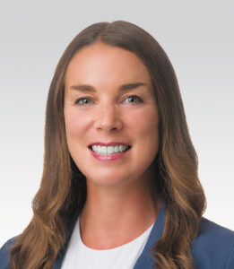 Headshot of occupational therapist Kari Brouwer wearing a white shirt and blue jacket against a white background.
