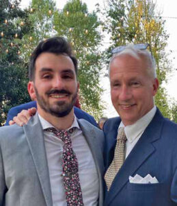 Andrew Zaleski and his father pose with arms around each other, both wearing suits and ties.