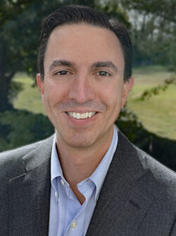 Headshot of Justin Giovannelli outdoors wearing a great suit jacket and light blue shirt.