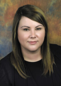 Headshot of Shannon Wood wearing a black top against a background of fall colors.