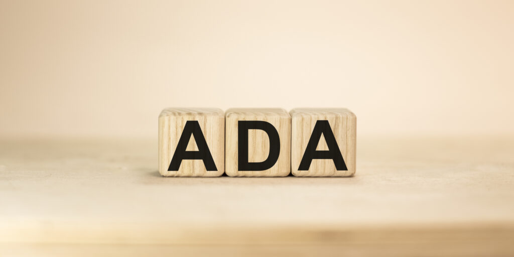 Word ADA on wooden blocks beige background top view