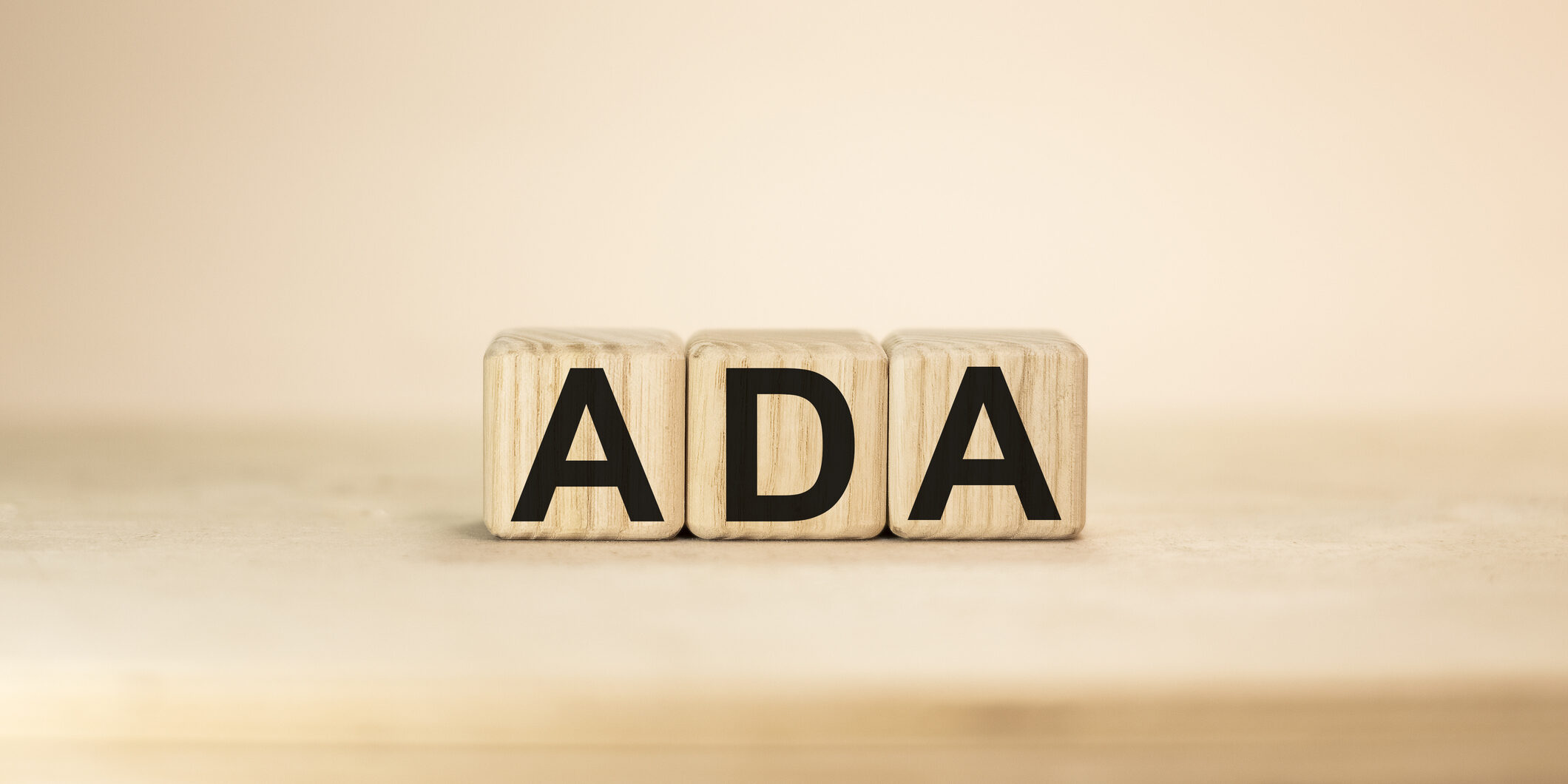 Word ADA on wooden blocks beige background top view