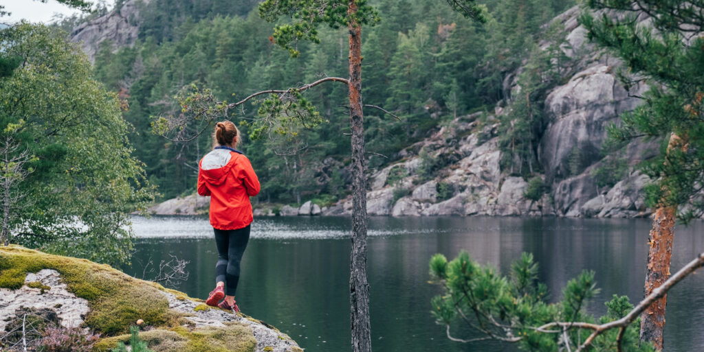 Young tourist female enjoying picturesque Norwegian wild lake in Telemark region, Norway. Traveling in Scandinavian countries concept image.