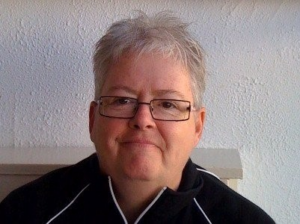 Closeup of Allison Nichol indoors wearing glasses and a black jacket.
