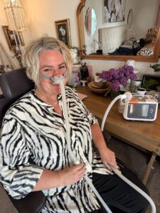Lacey Woods wears a nasal mask while using breathing support.