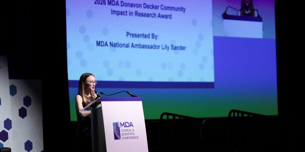 A young woman stands at a podium on stage at a conference