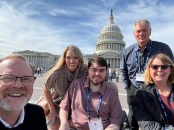 A group of advocates stand in front of the Capitol building