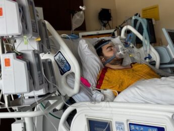 A young man in a hospital bed with a ventilator to breathe