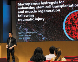 John presenting his thesis on stem cell transplantation and muscle regeneration to an auditorium audience.
