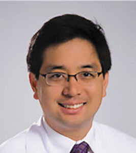 Headshot of neurologist Perry Shieh wearing glasses and a white button-down with a purple tie against a light gray background.