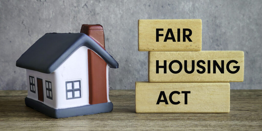 Fair Housing Act Text with Miniature House on Wooden Table and Gray Background