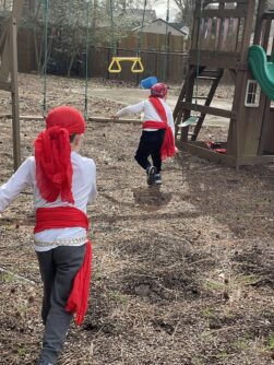 Two young boys dressed as pirates run towards a playground